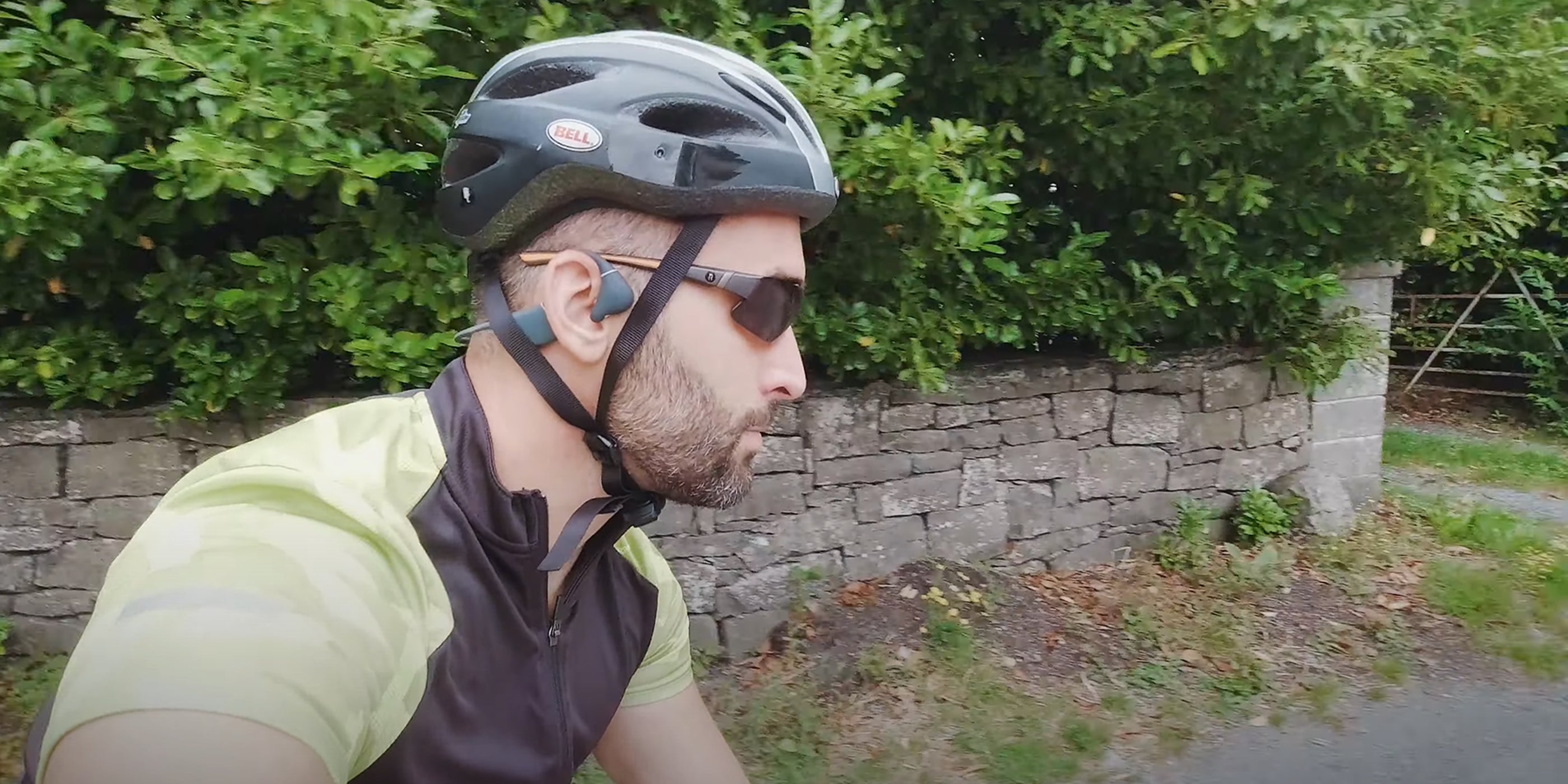 A cyclist is riding a bike wearing bone conduction headphones