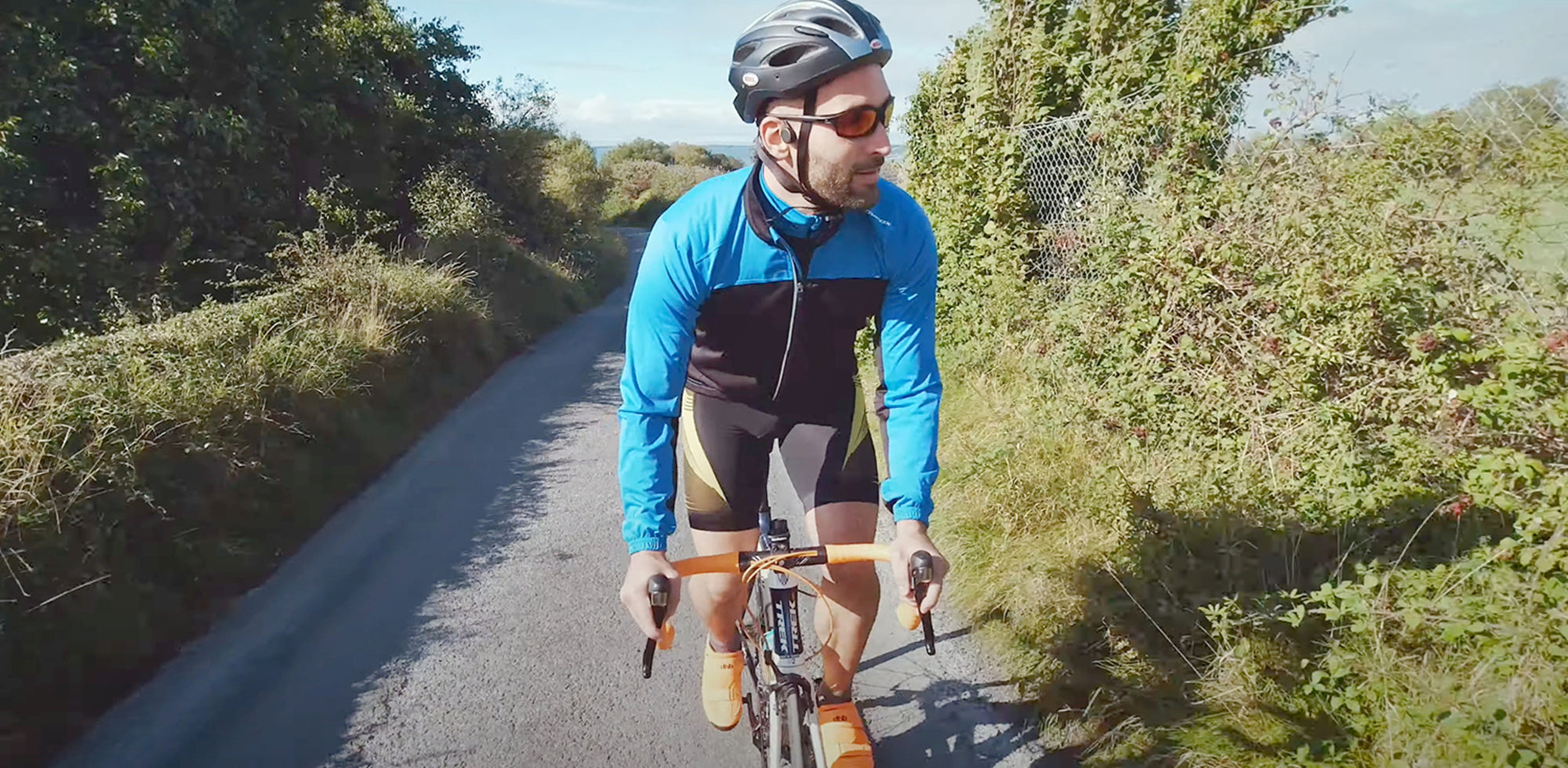 A cyclist is riding a bike wearing bone conduction headphones