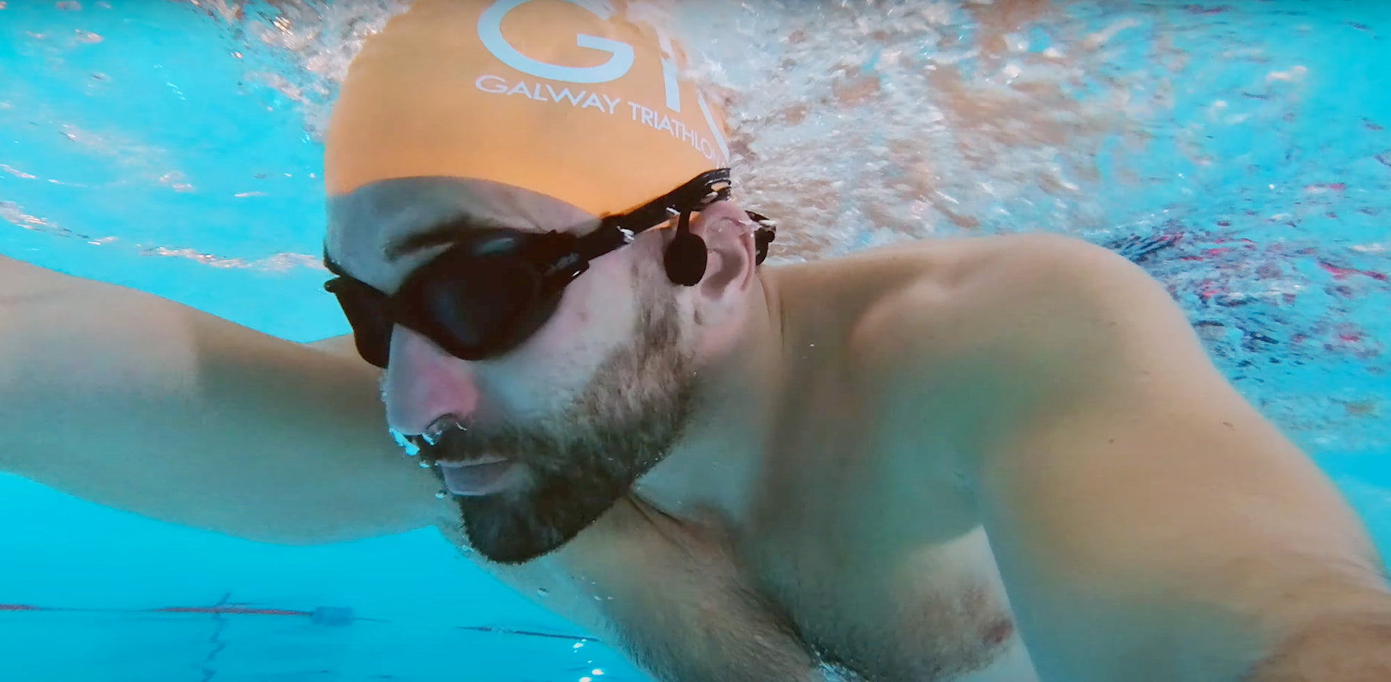 Swimmers are swimming wearing bone conduction swimming headphones